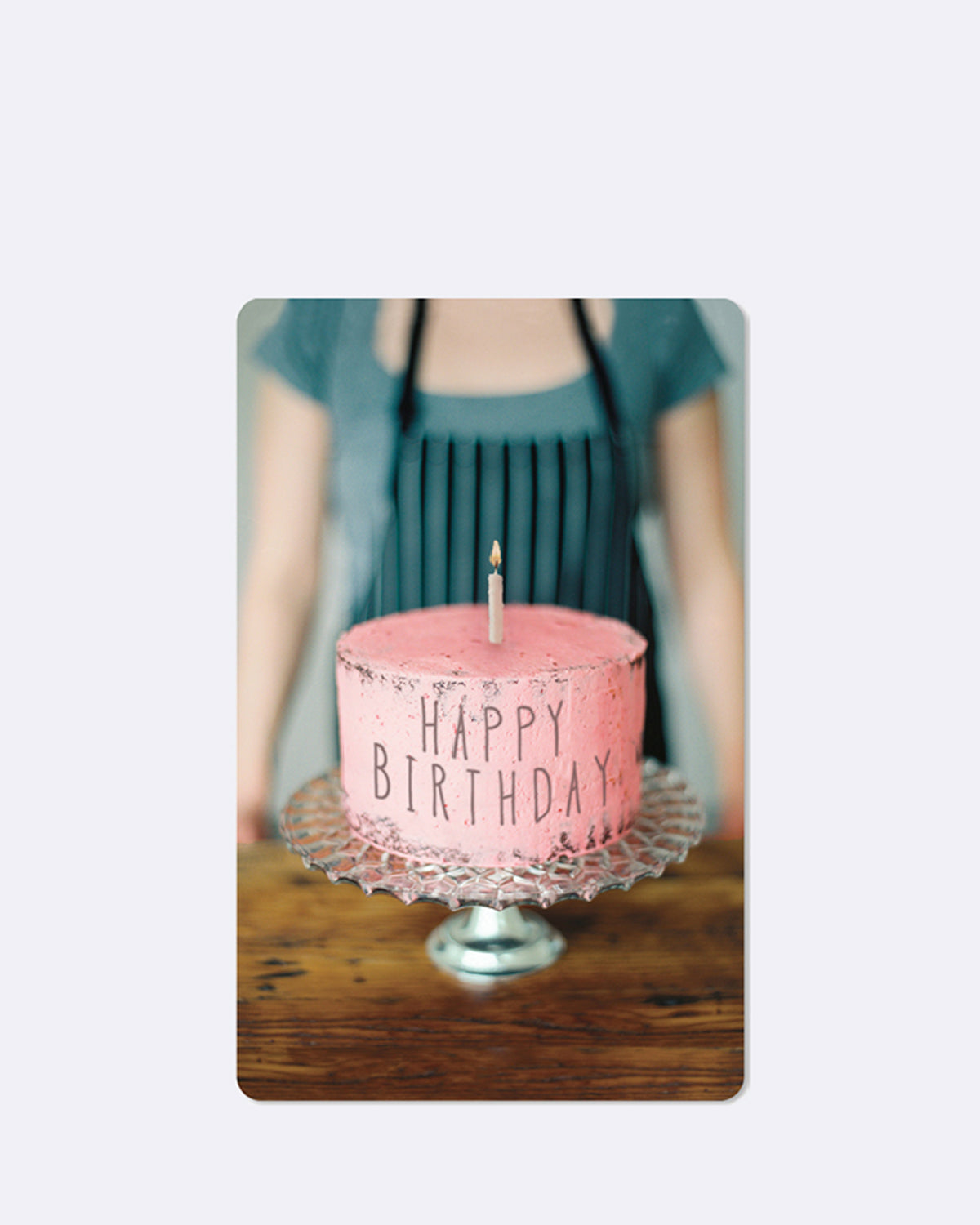 Postkarte mit einer Torte im Vordergrund und einer Frau im Hintergrund 